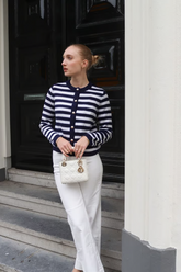 a lady in a striped cardigan and a pair of white pants
